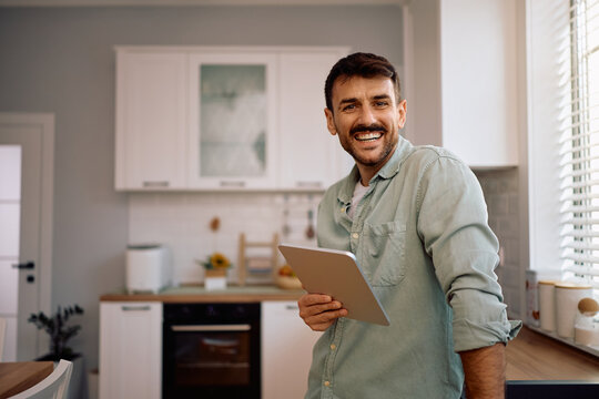Happy man with digital tablet at home looking at camera. - Powered by Adobe