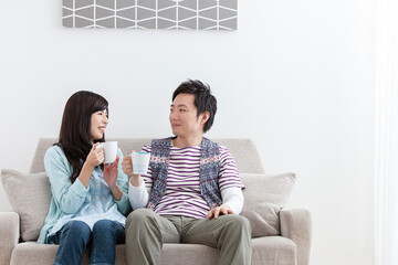 ソファでコーヒーを飲む夫婦