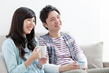 ソファでコーヒーを飲む夫婦