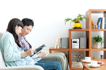 ソファで本を見る夫婦