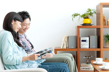 ソファで本を見る夫婦