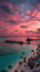 Aerial view of a tropical beach resort at sunset. Vivid pink and orange clouds over turquoise water.  Palm trees line the shore