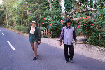 Two people enjoy an outdoor setting while engaging in conversation alongside a peaceful forest road