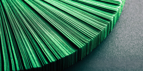 Stack of green folded paper sheets displayed in a radial abstract pattern, emphasizing texture, order, and minimalist design.