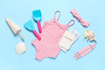 Composition with children's swimsuit, beach accessories and toys on blue background