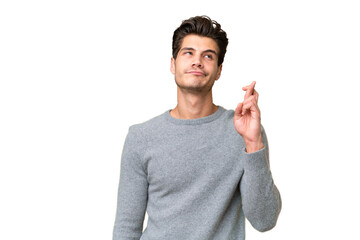 Young handsome caucasian man over isolated background with fingers crossing and wishing the best