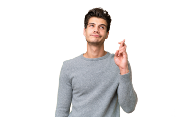 Young handsome caucasian man over isolated background with fingers crossing and wishing the best