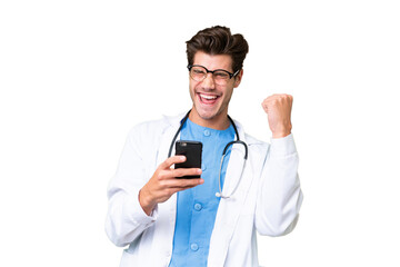 Young doctor man over isolated background with phone in victory position