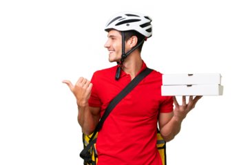 Pizza delivery man with work uniform picking up pizza boxes over isolated background pointing to the side to present a product