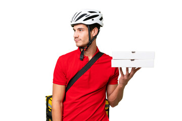 Pizza delivery man with work uniform picking up pizza boxes over isolated background looking to the...