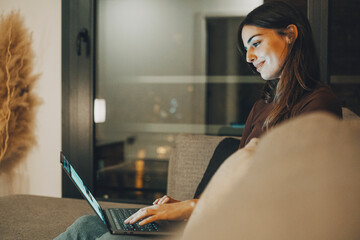 Young woman alone at home working late at night on her laptop. Freelancing, studying, chatting...