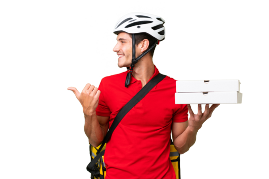 Pizza delivery man with work uniform picking up pizza boxes over isolated background pointing to the side to present a product