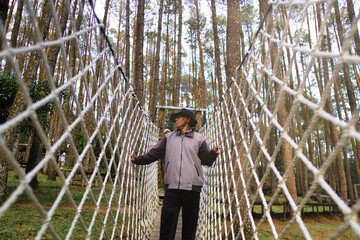 Man Walking on Rope Bridge in Forest Wooded Area