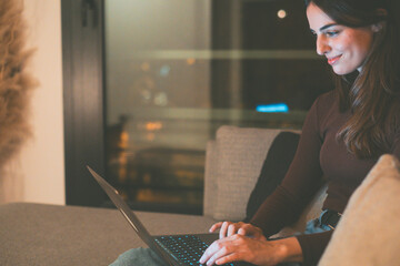 Young woman alone at home working late at night on her laptop. Freelancing, studying, chatting...