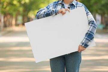 Young woman holding blank poster on city street