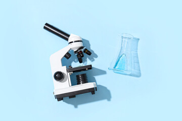 Modern microscope and flask on blue background