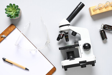Modern microscope, clipboard and test tubes with blood samples on white background