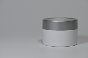 Cosmetic cream jar with silver lid on neutral background