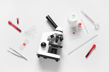Modern microscope and test tubes with blood samples on white background