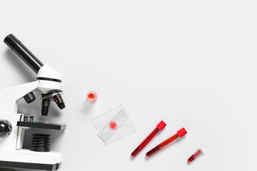 Modern microscope and test tubes with blood samples on white background