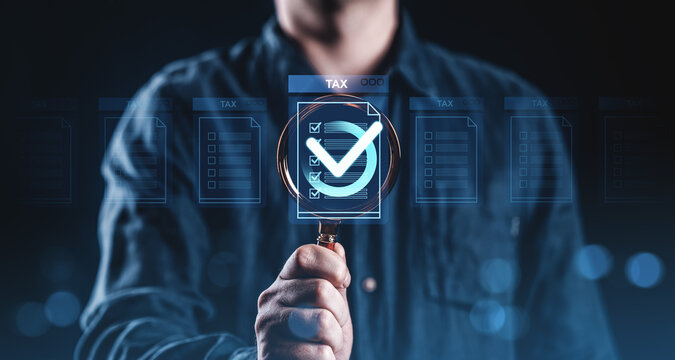 Businessman holding magnifying glass over virtual tax checkmark form, illustrating tax compliance and audit concept on dark blue background..