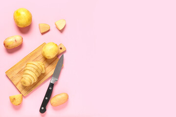 Wooden board with raw baby potatoes on pink background