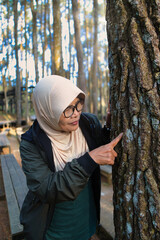 Woman in Headscarf Observing a Tree Bark in a Forested Park