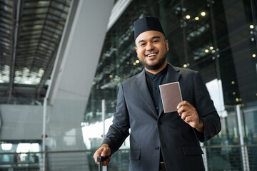 Muslim asian businessman traveler holding boarding pass ticket, passport and smartphone at the...