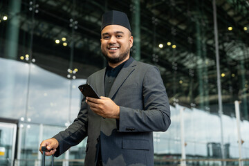 Muslim asian businessman traveler holding boarding pass ticket, passport and smartphone at the...