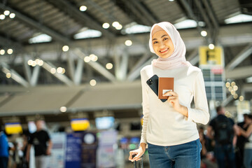 Muslim asian businesswoman traveler holding boarding pass ticket, passport and smartphone at the...