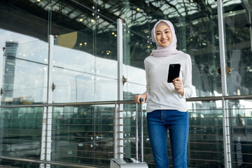 Muslim asian businesswoman traveler holding boarding pass ticket, passport and smartphone at the...