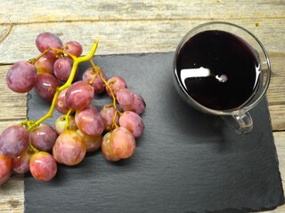 Beautiful juicy pink grapes on a cutting board, next to a cup of freshly squeezed juice