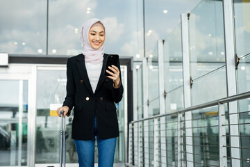 Muslim asian businesswoman traveler holding boarding pass ticket, passport and smartphone at the...
