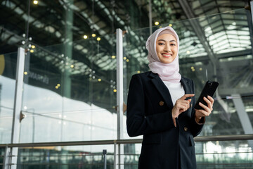 Muslim asian businesswoman traveler holding boarding pass ticket, passport and smartphone at the...