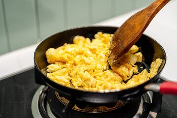 A hand gently folds a fluffy omelet in a pan, beside a perfectly sizzling fried egg. Close-up A...