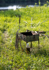 tourist small barbecue and grill for cooking on fire stand on grass
