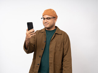 Young asian man using smartphone standing on isolated white background. He texting on cell phone. Dressing with jacket and jean.