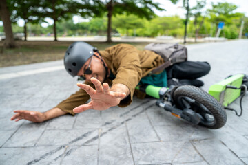 Young Asian Businessman falling off EV scooter on the road. Accident Injury leg pain. Broken leg falls off the Scooter. Accident on the road.