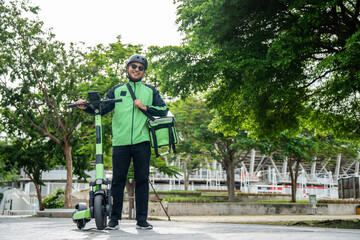Rider food delivery man wearing green uniform and helmet ride the EV scooter delivery food service to customer. Happy delivery man with green backpack shipping of goods to customers by scooter