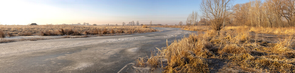 lake in autumn steppe covered with ice at dawn
