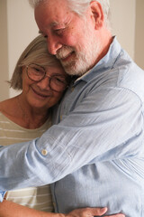 Senior couple in their 70s sharing loving and tender moments at home. A heartwarming scene of...