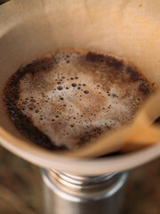 Close up of bubbling ground coffee inside paper filter during outdoor brew process