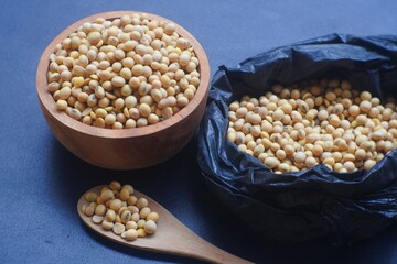 open soybeans in black plastic bag and wooden bowl