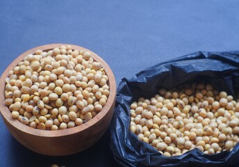 open soybeans in black plastic bag and wooden bowl