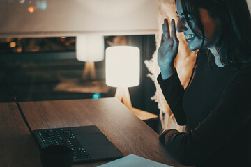 Young woman alone at home working late at night on her laptop. Freelancing, studying, chatting...
