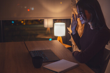 Young woman alone at home working late at night on her laptop. Freelancing, studying, chatting...