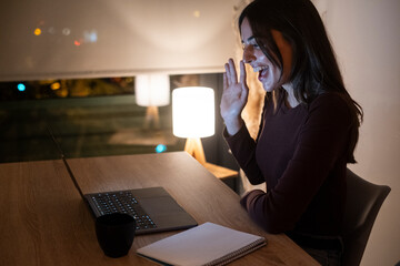 Young woman alone at home working late at night on her laptop. Freelancing, studying, chatting...