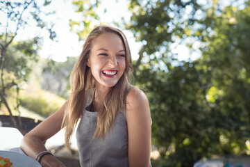 Naklejka premium Female sitting at backyard patio table, turning head, smiling with bowl of citrus fruit