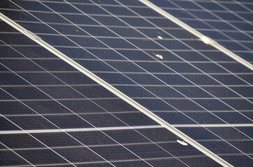 A solar panel with a black and white grid pattern. The panel is dirty and has some dirt on it