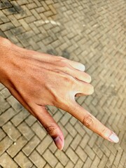 Creative hand pose captured on outdoor textured pavement, useful for body movement or directional...